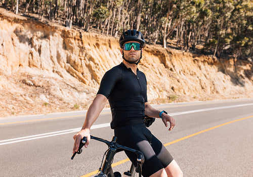 Young male professional cyclist relaxing after ride