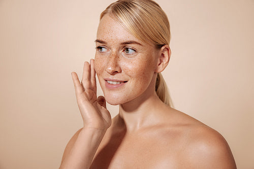 Smiling woman touching her face with finger while standing in st