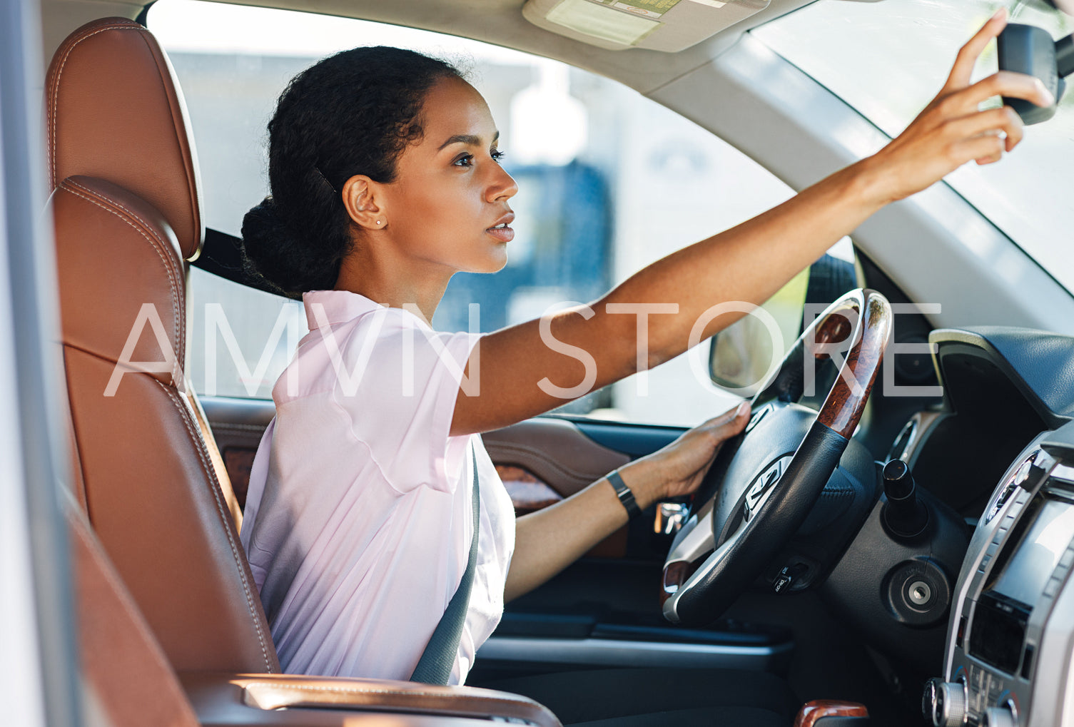 Side view of woman adjusting rear view mirror while driving a car	