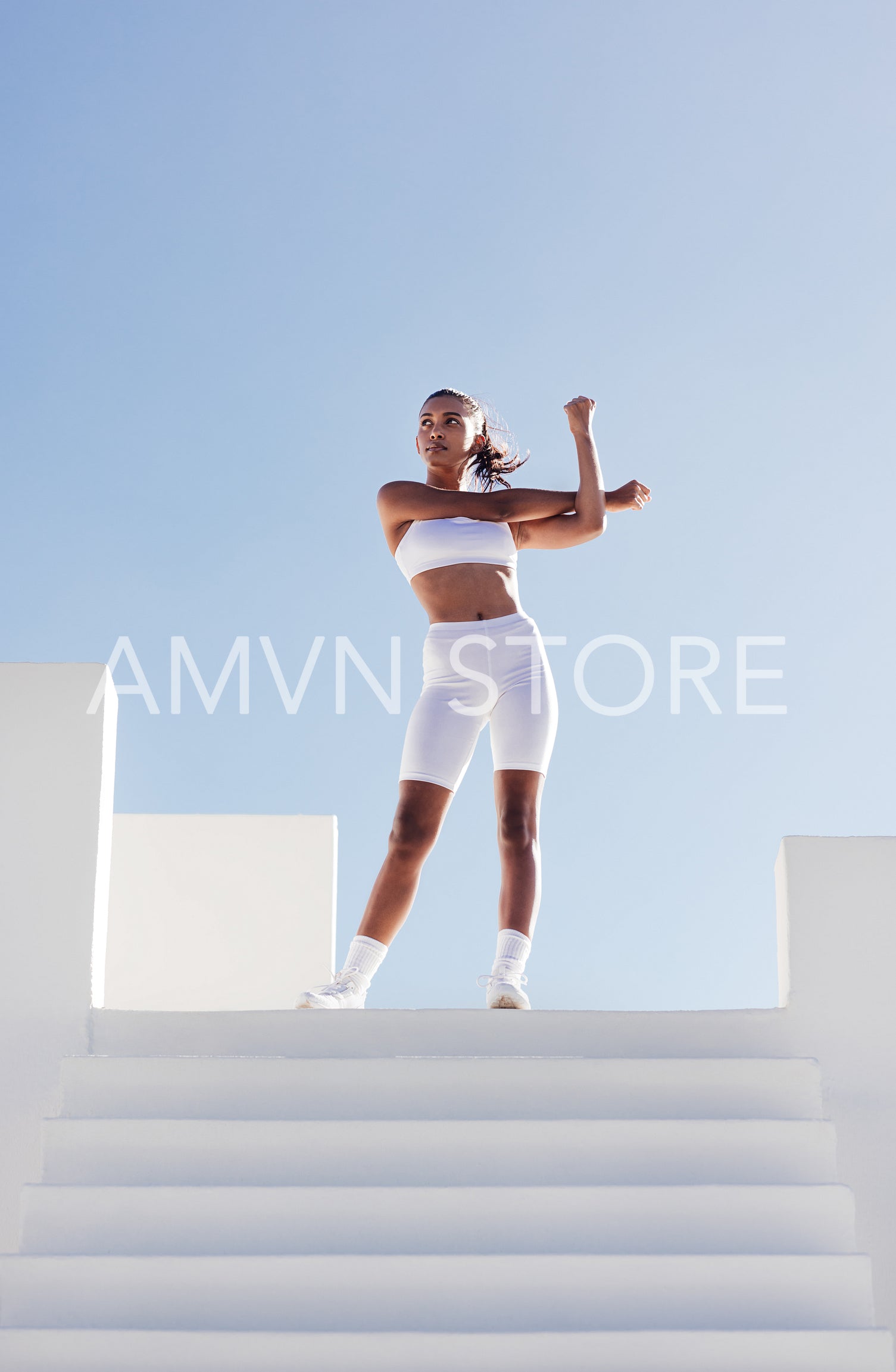 Full length of a slim woman warming up hands against skies. Young slim female stretching her hand while standing on the top of stairs.