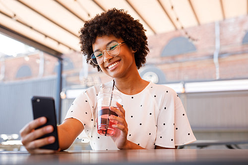 Young blogger making photos for social media, sitting at outdoor cafe