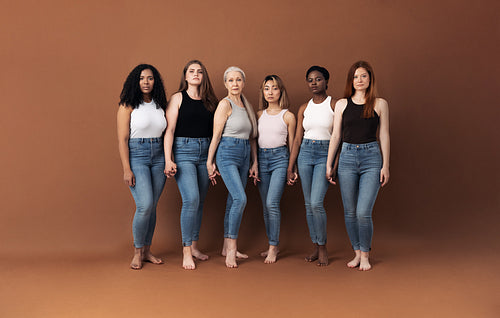 Six serious women standing together holding hands in studio