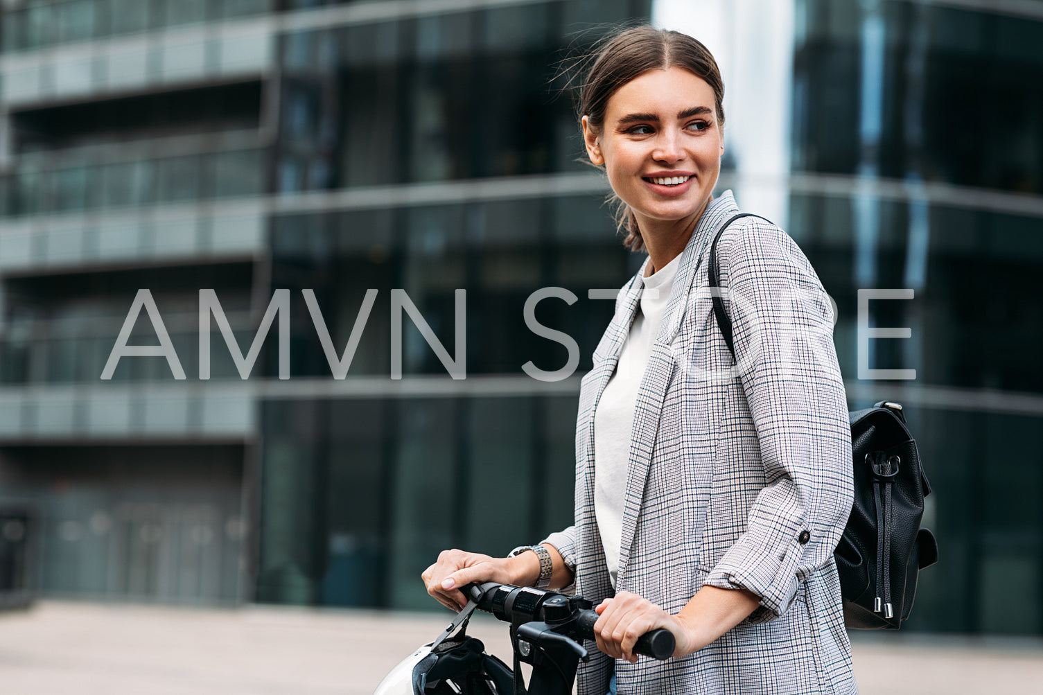 Happy woman in formal wear holding the handlebar and looking away while standing against an office building