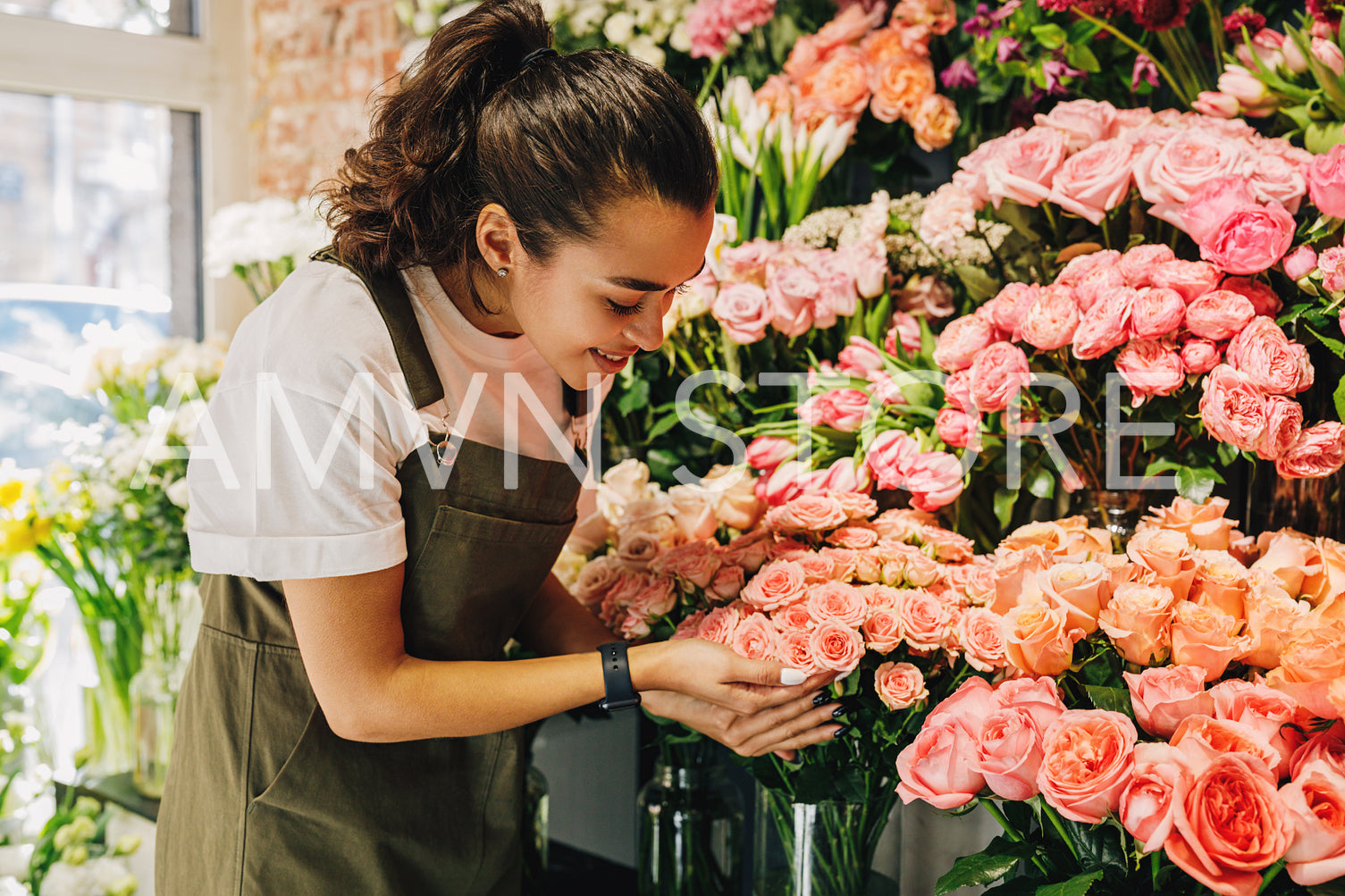 Smiling florist woman looking on a bunch of flowers in her shop