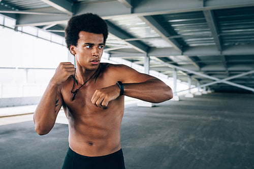 Young sportsman warming up under a bridge, doing boxing exercises