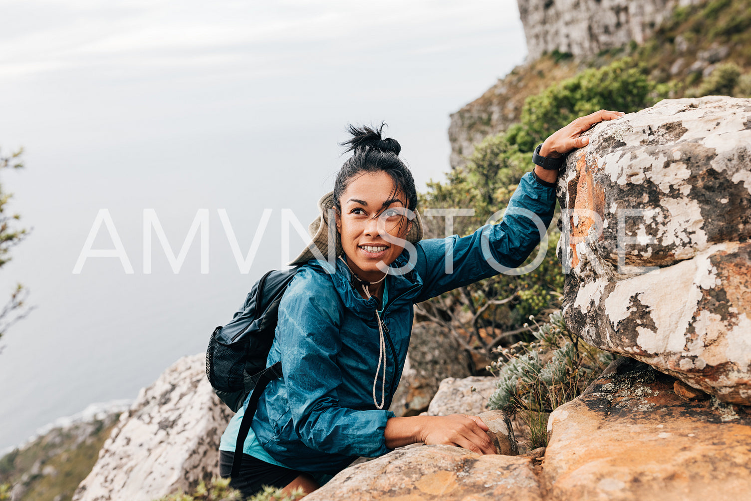 Portrait of a woman with backpack and sports clothes climbing up on a mountain