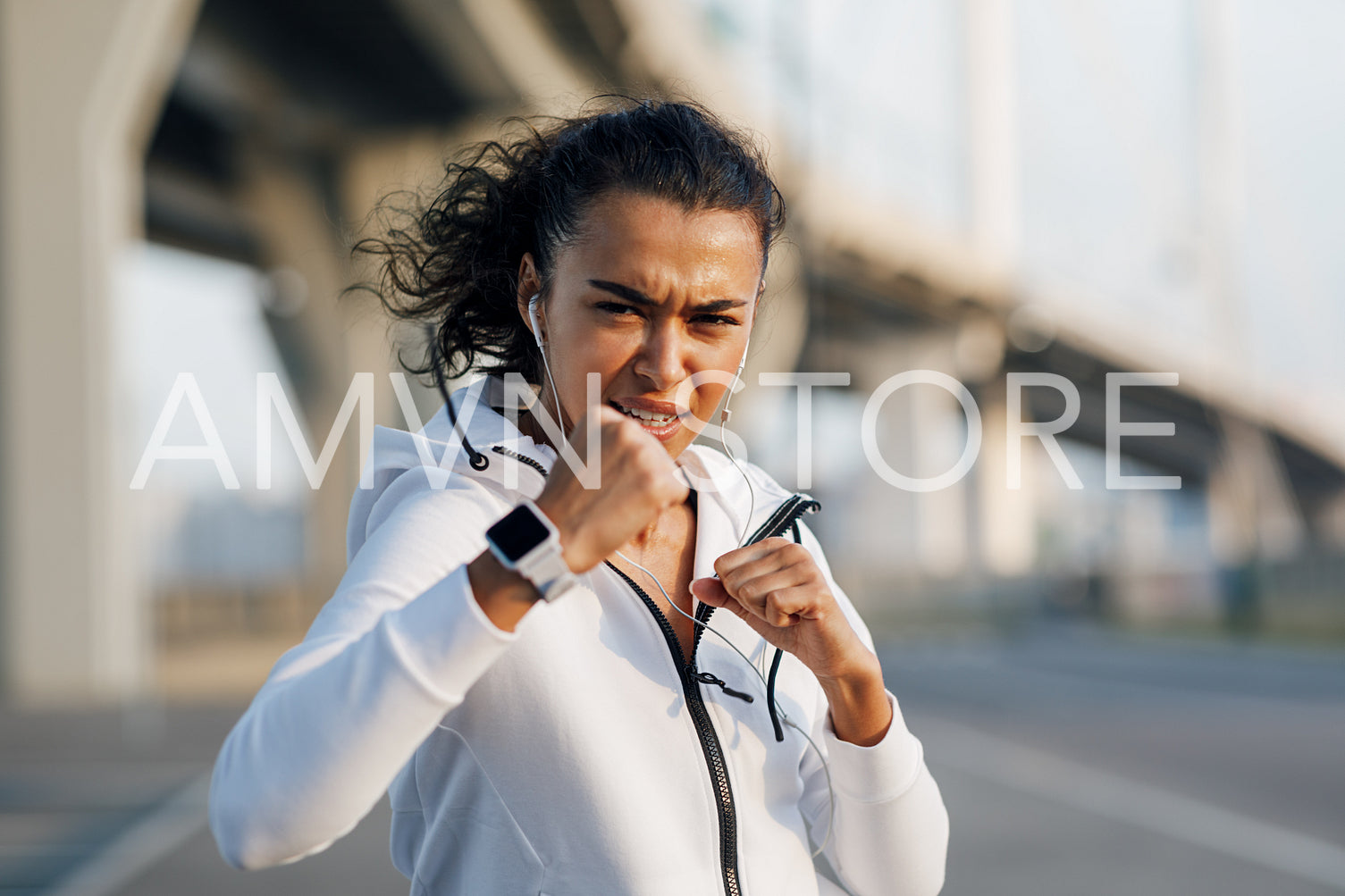 Young sportswoman training boxing moves outdoors. Woman practicing punches at evening on a city street.