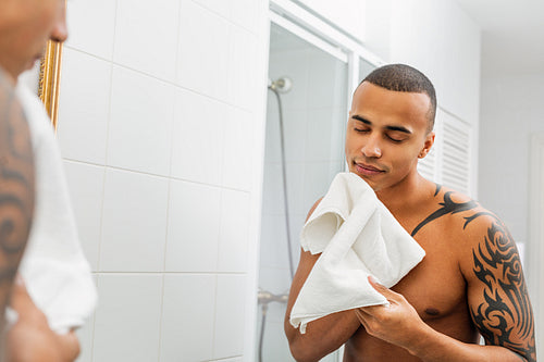 Young handsome man drying his face with white towel after shaving