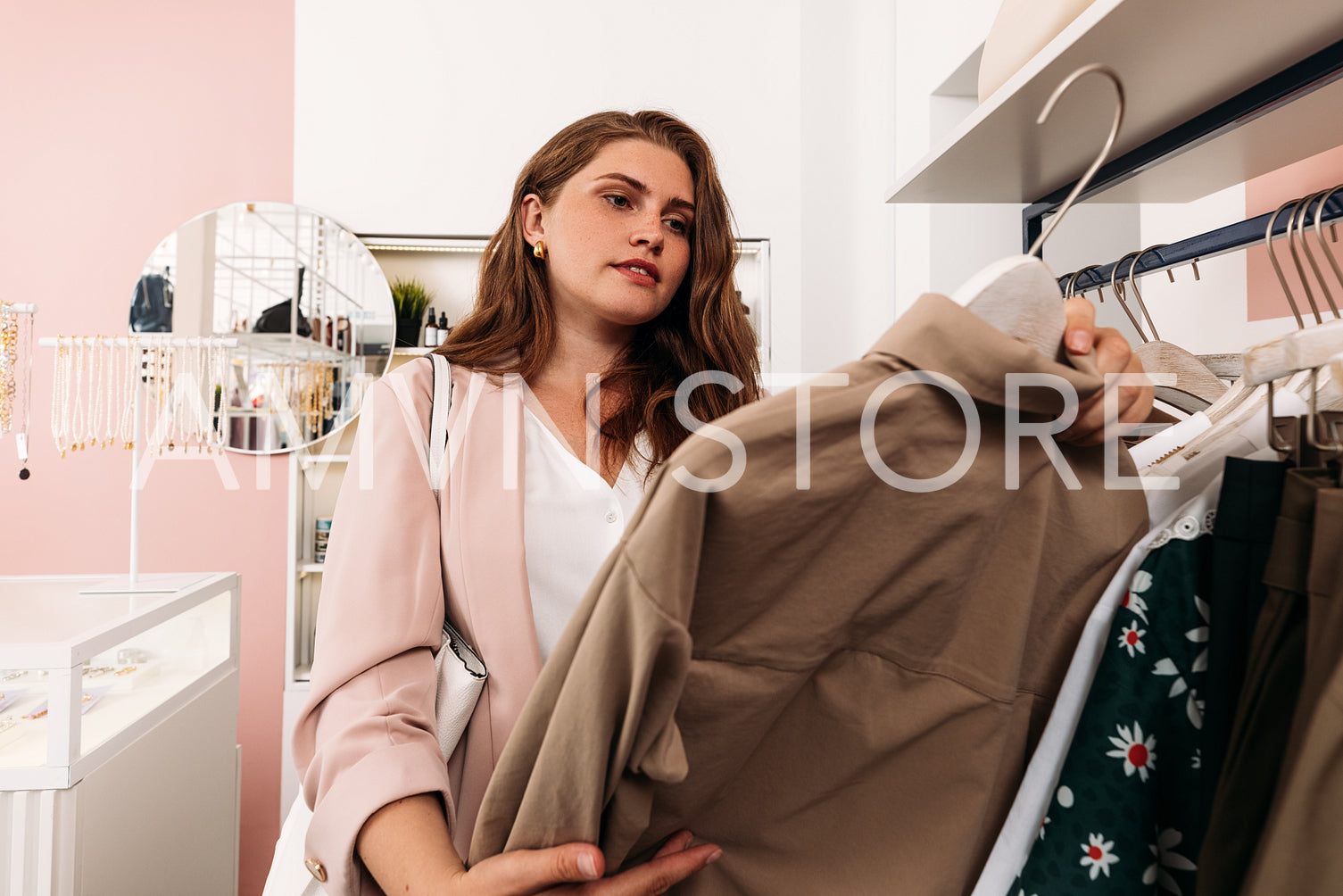 Young woman holding a hanger in small boutique choosing clothes