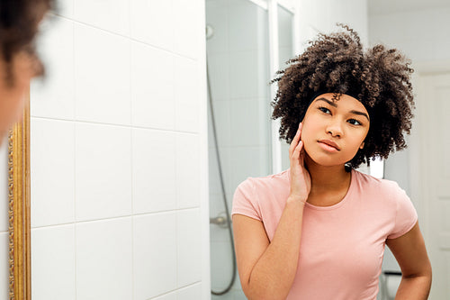 Girl with hair bandage observing her face in mirror