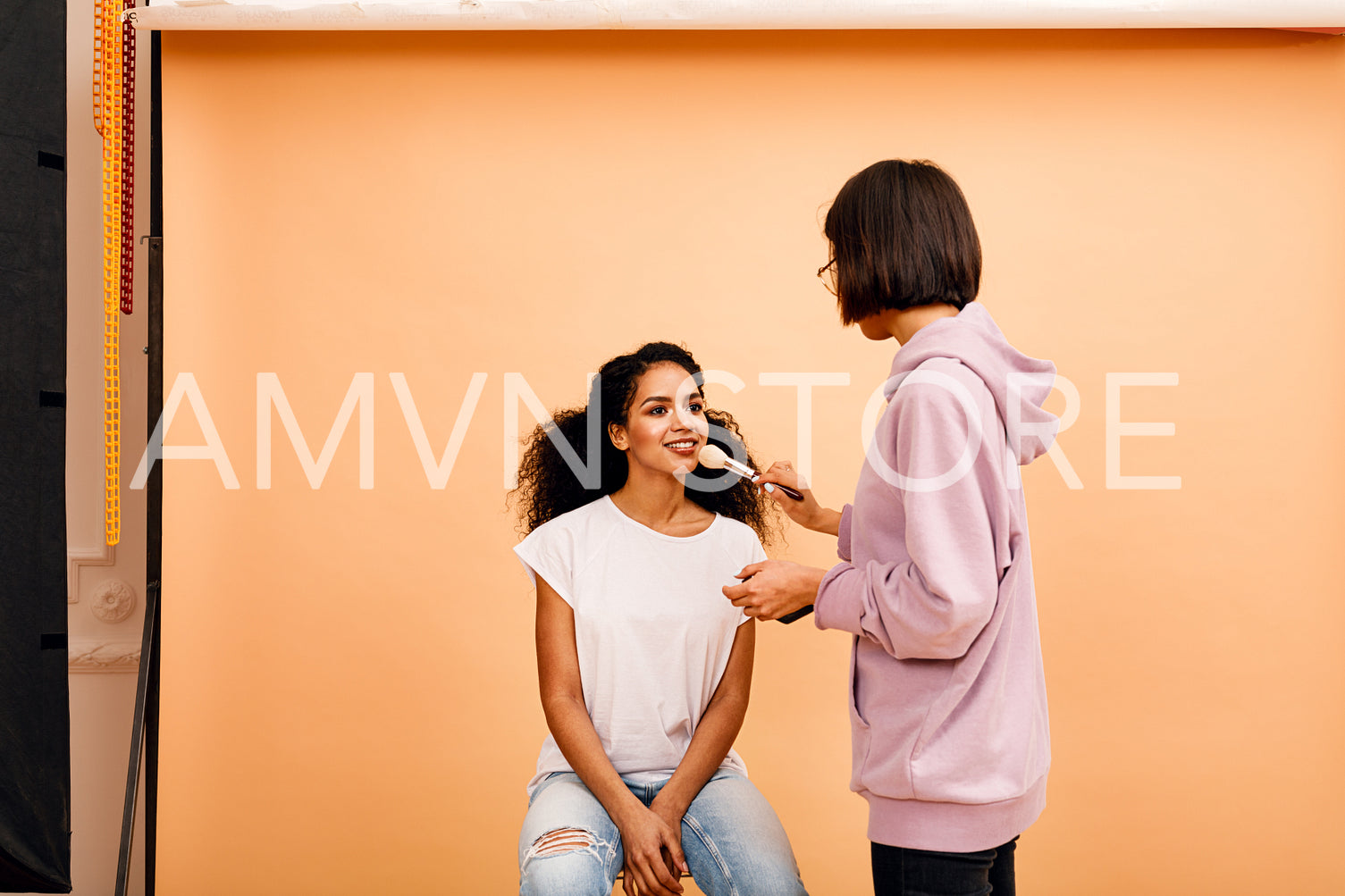 Makeup artist in studio. Two people preparing for photoshoot.	