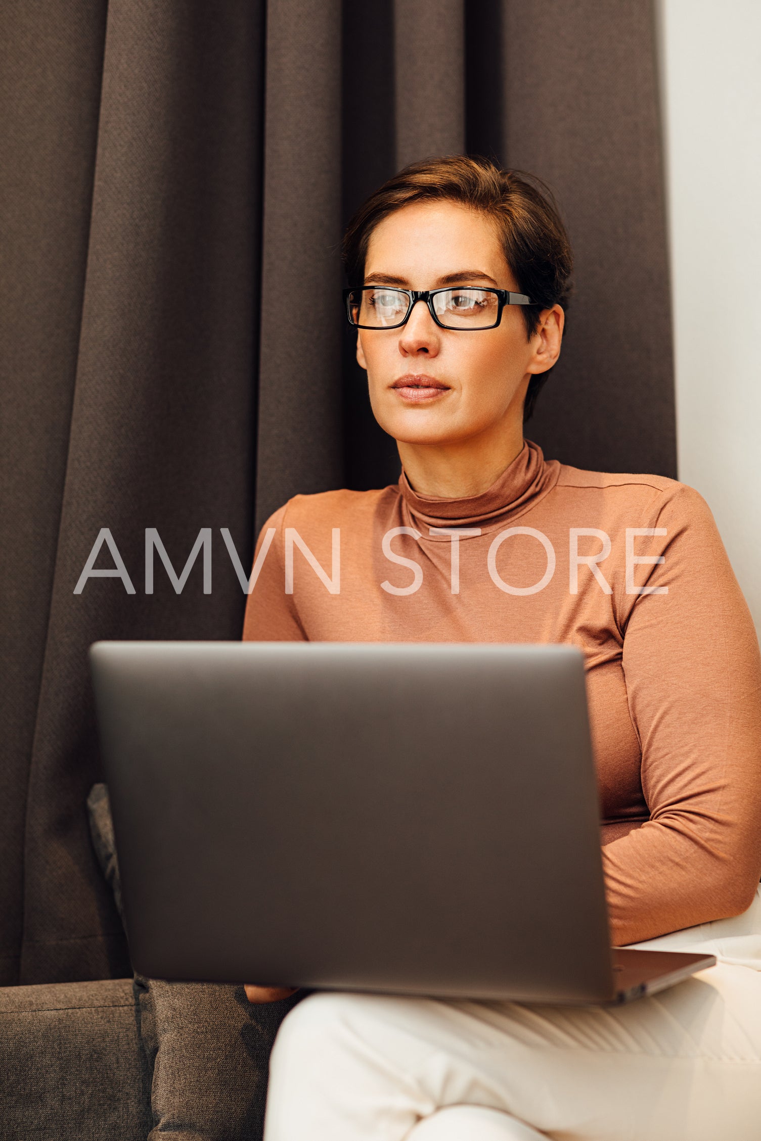 Young woman sitting on sofa in hotel room using laptop	