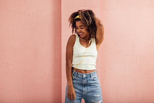 Female with curly hair listening to music, smiling, and looking