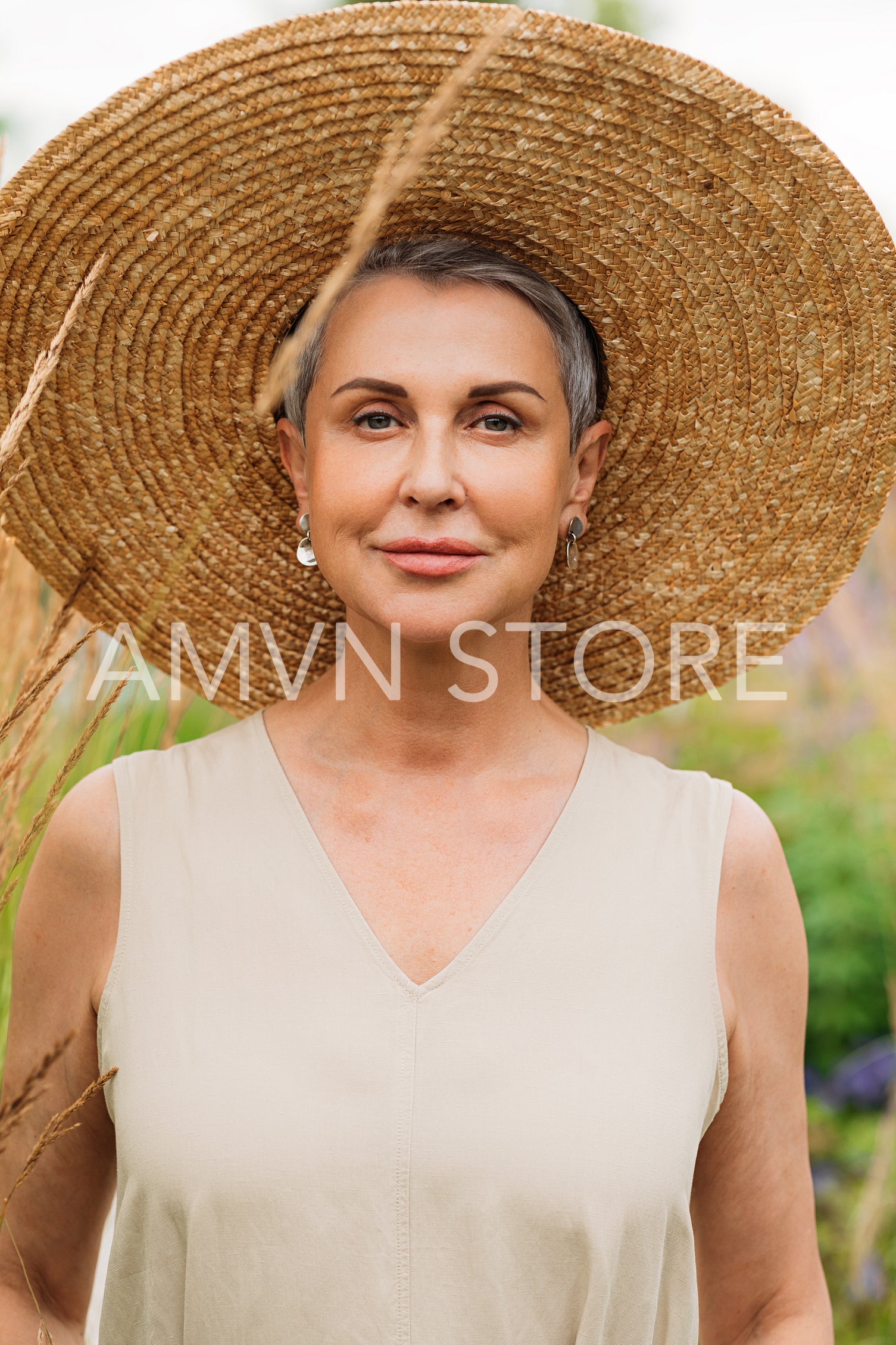 Portrait of a mature female in big straw hat standing outdoors in the field