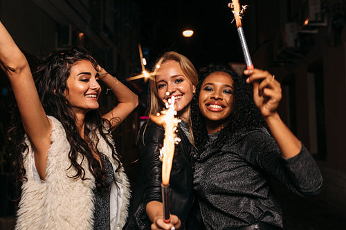 Group of female friends with sparklers enjoying outdoor party at night