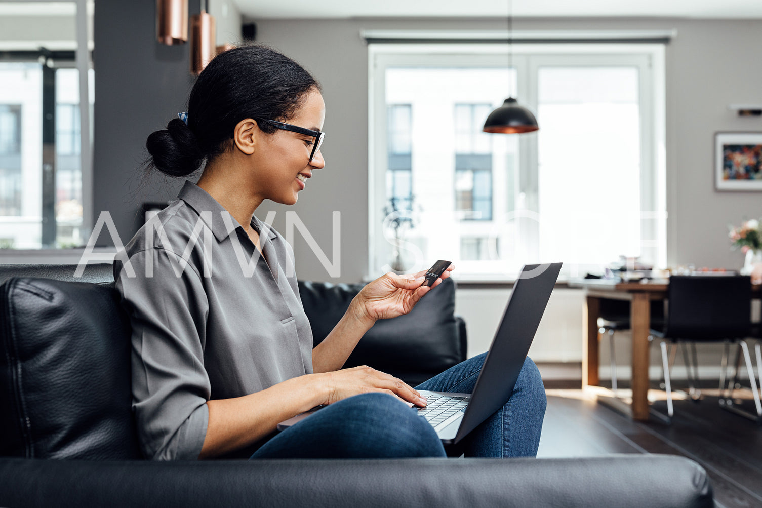 Side view of smiling woman holding a card using laptop on hips at home	