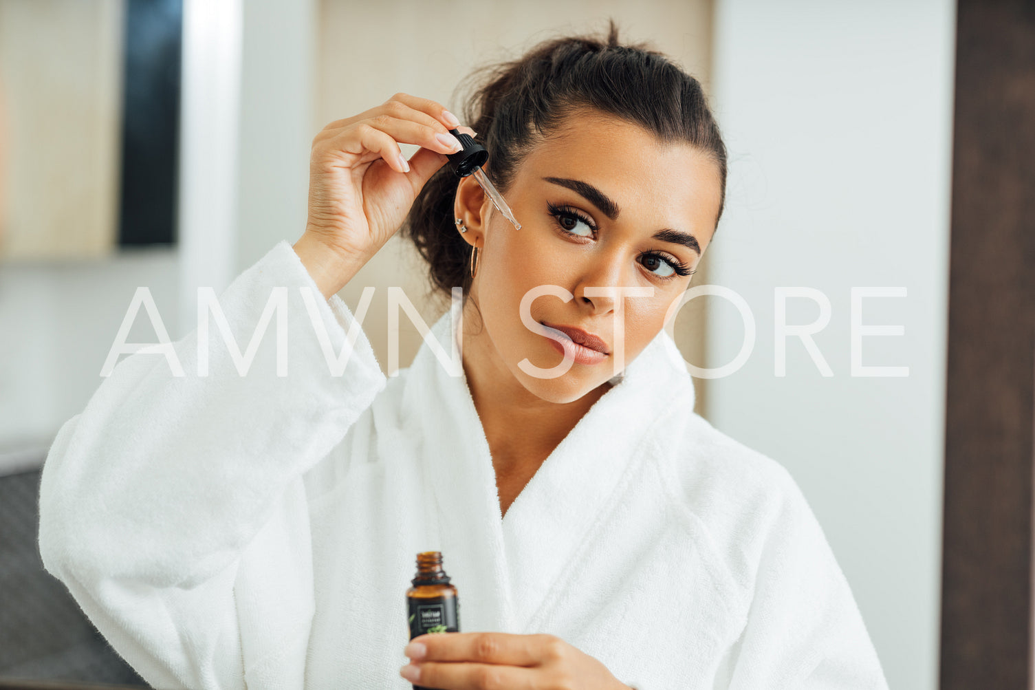 Beautiful woman using serum dropper in bathroom. Young female applying hyaluronic acid on her cheek.	