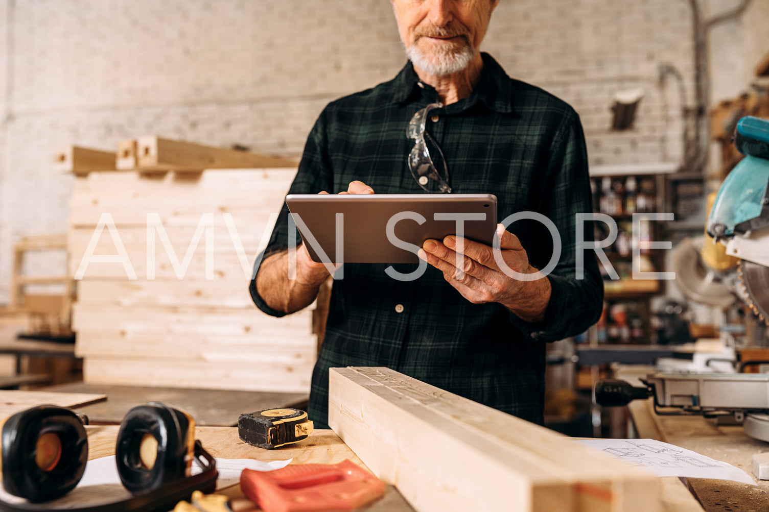 Cropped shot of a senior carpenter looking at digital tablet in his workshop	