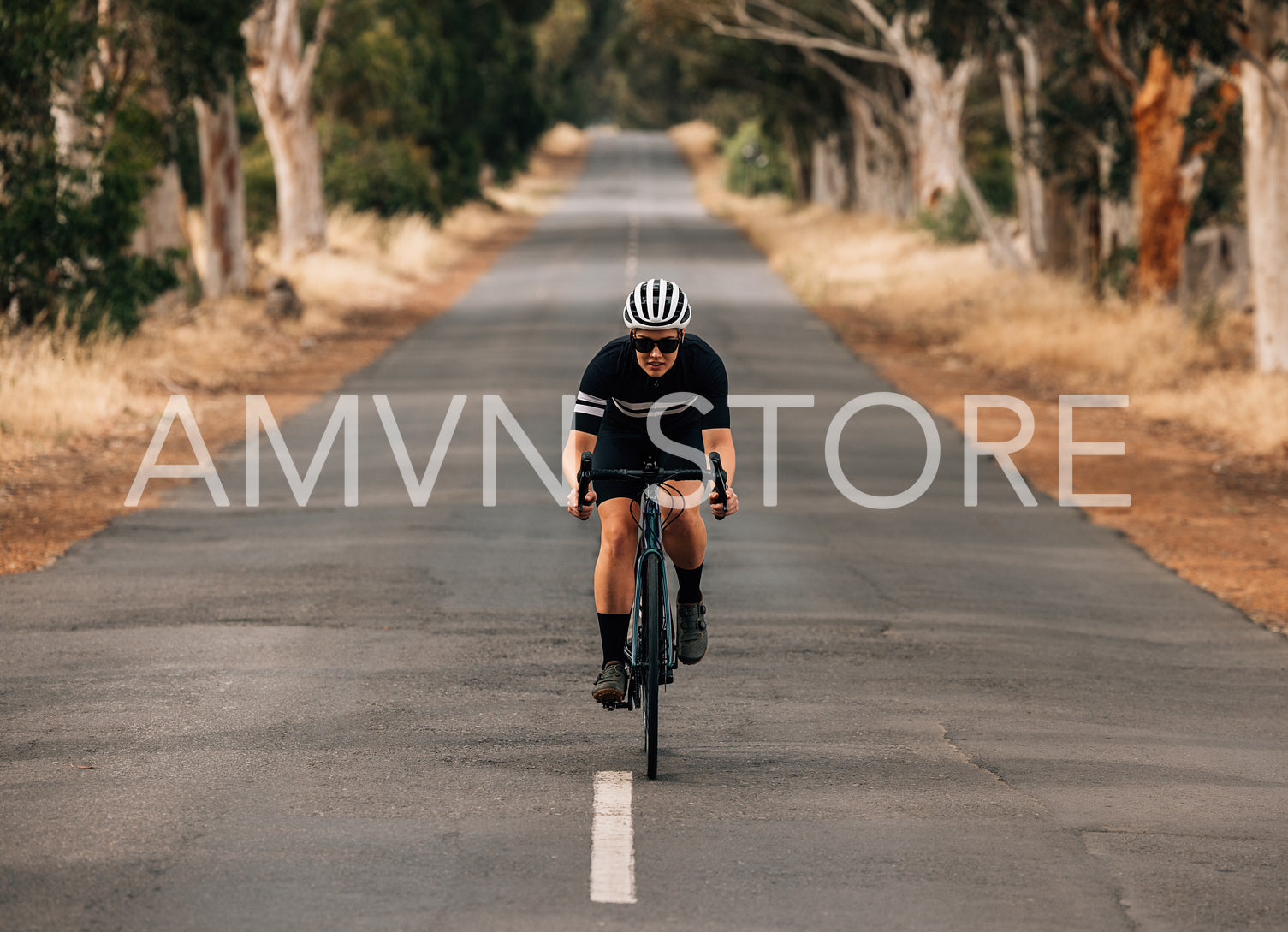 Athlete cycling on empty country road. Professional cyclist training outdoors.