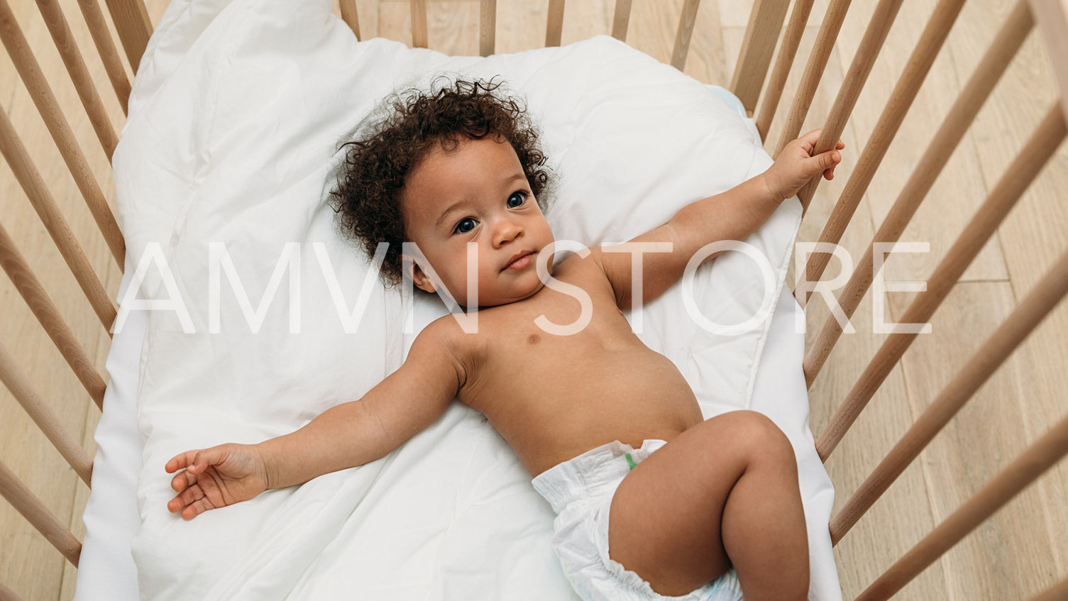 Curly haired baby boy lying in a crib	