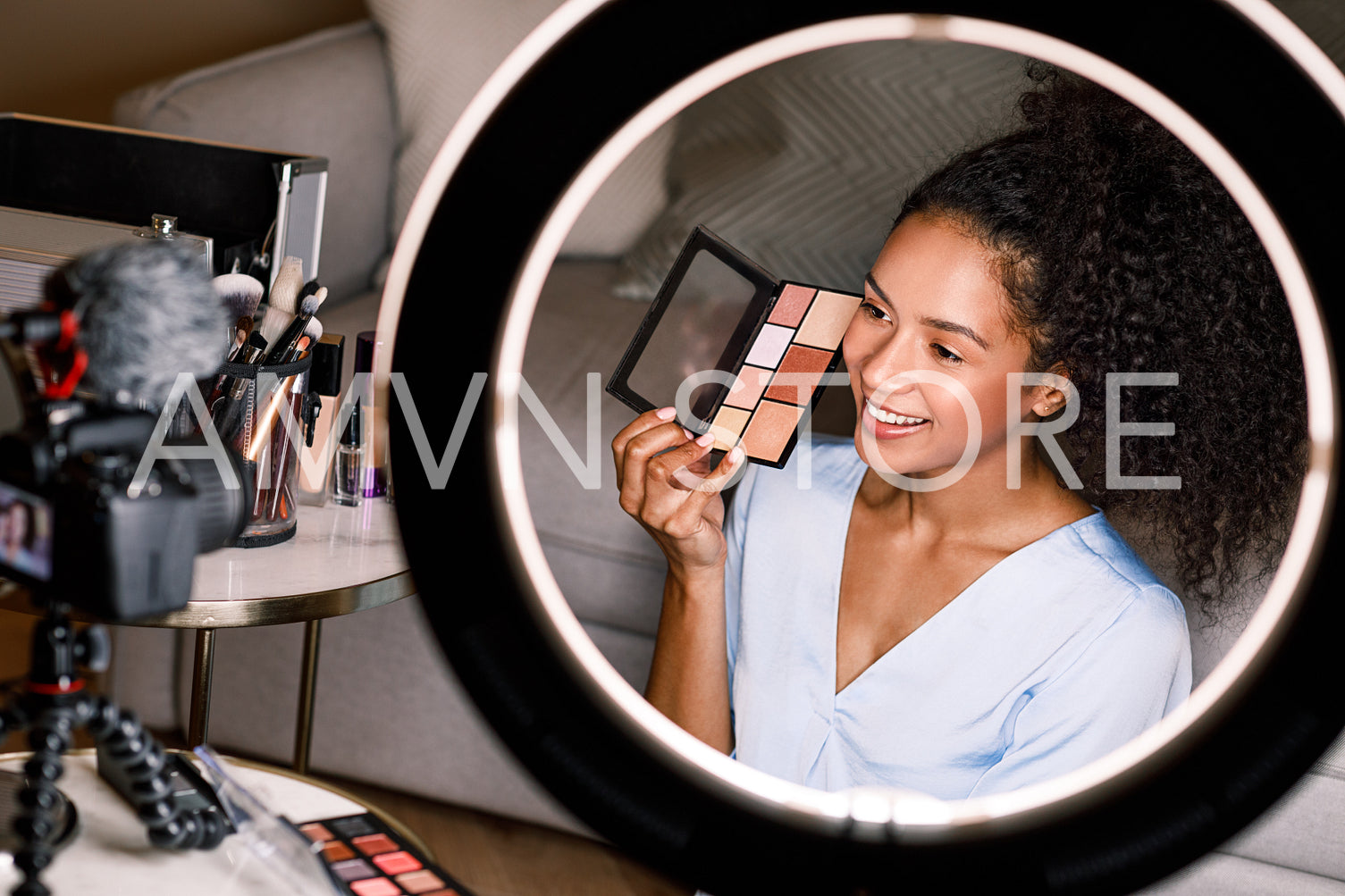 Young smiling woman showing a makeup palette on camera while recording video for beauty channel	