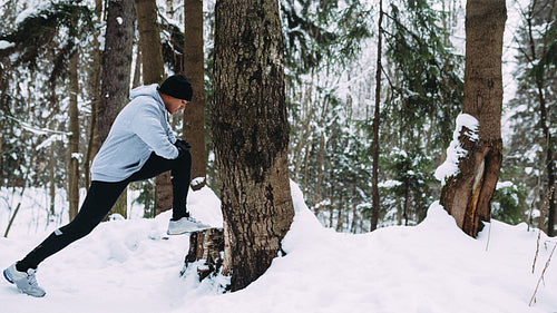 Young athlete warming up his legs before run in forest