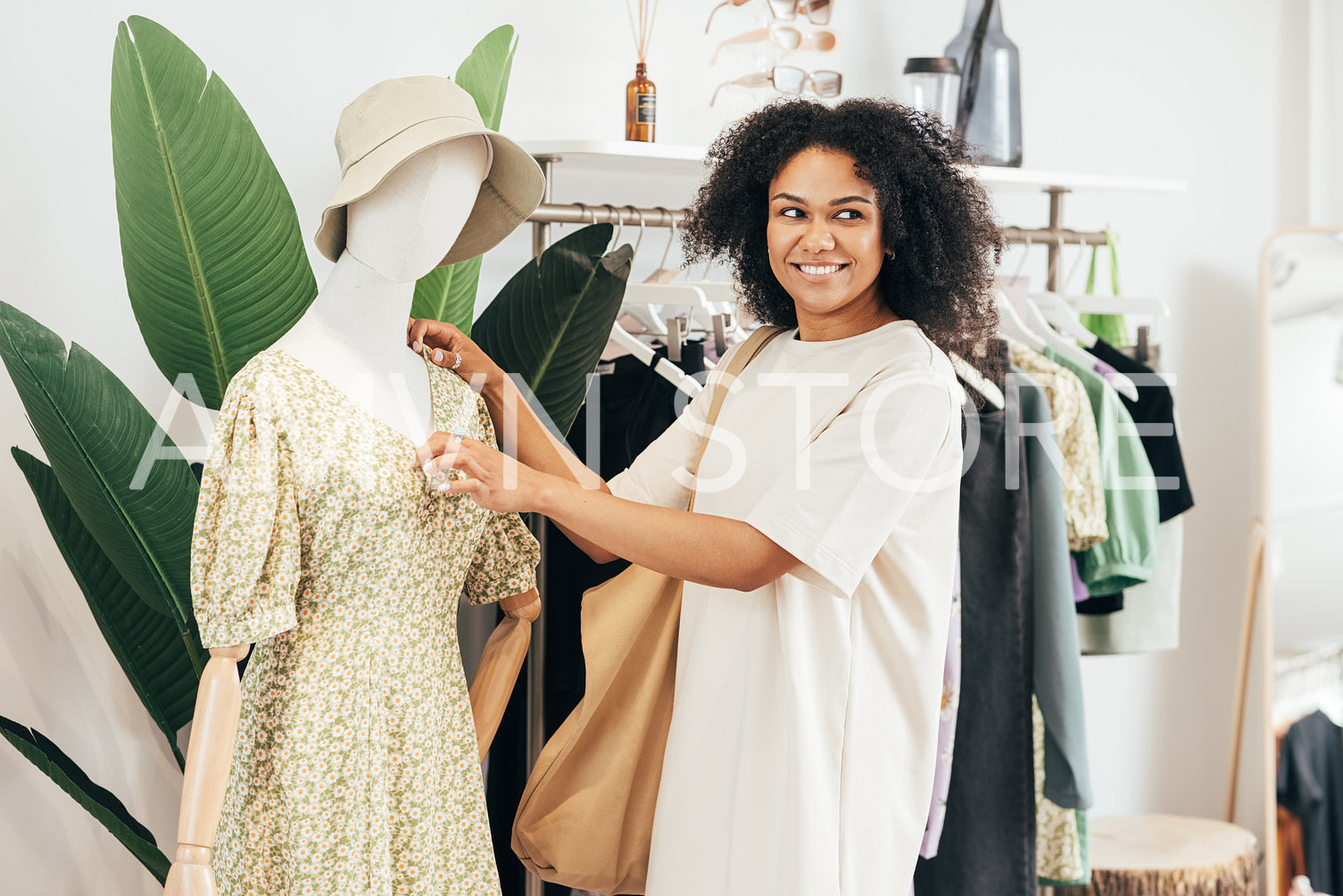 Smiling customer touching clothes on mannequin and looking away