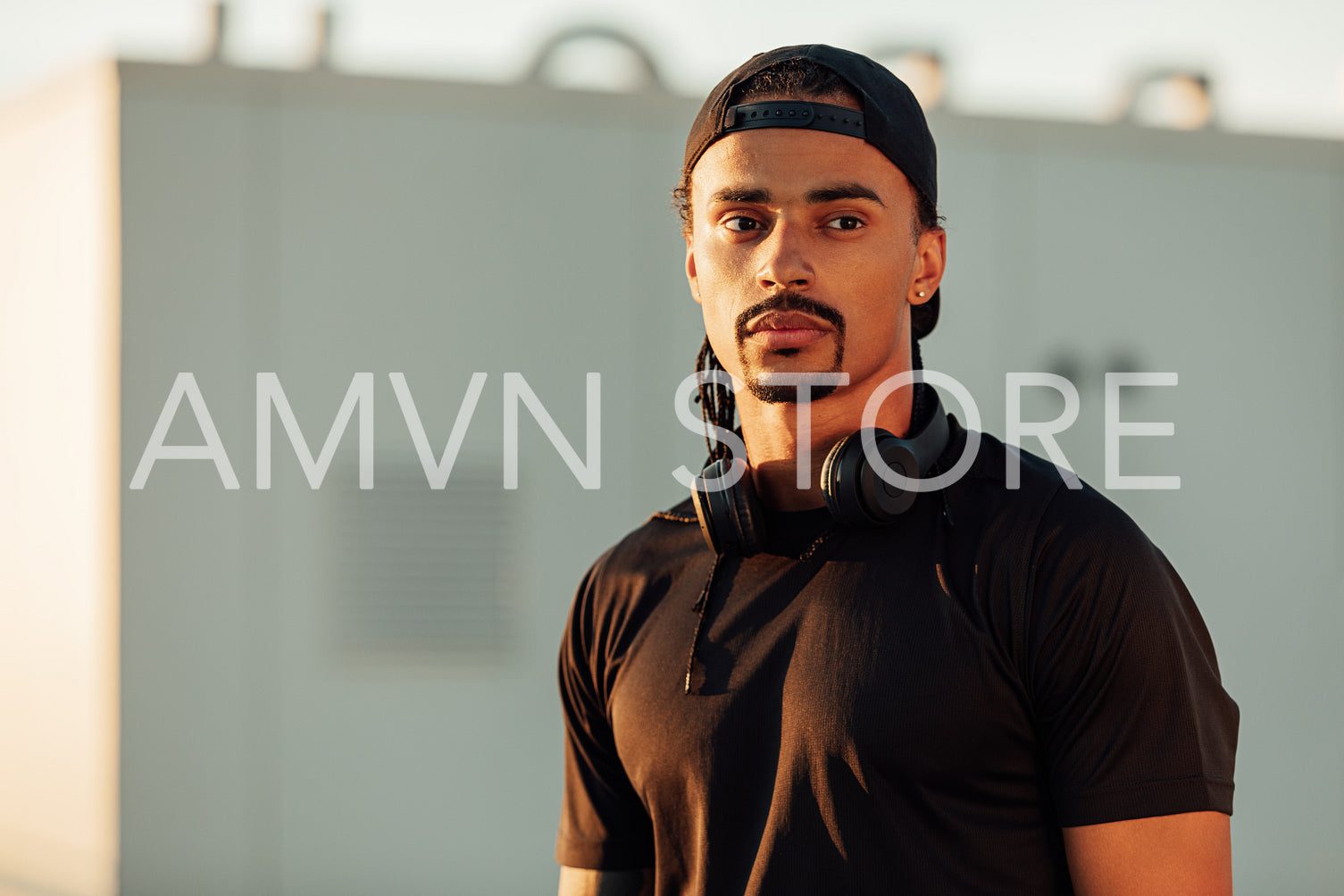 Portrait of a confident male athlete in a cap with headphones