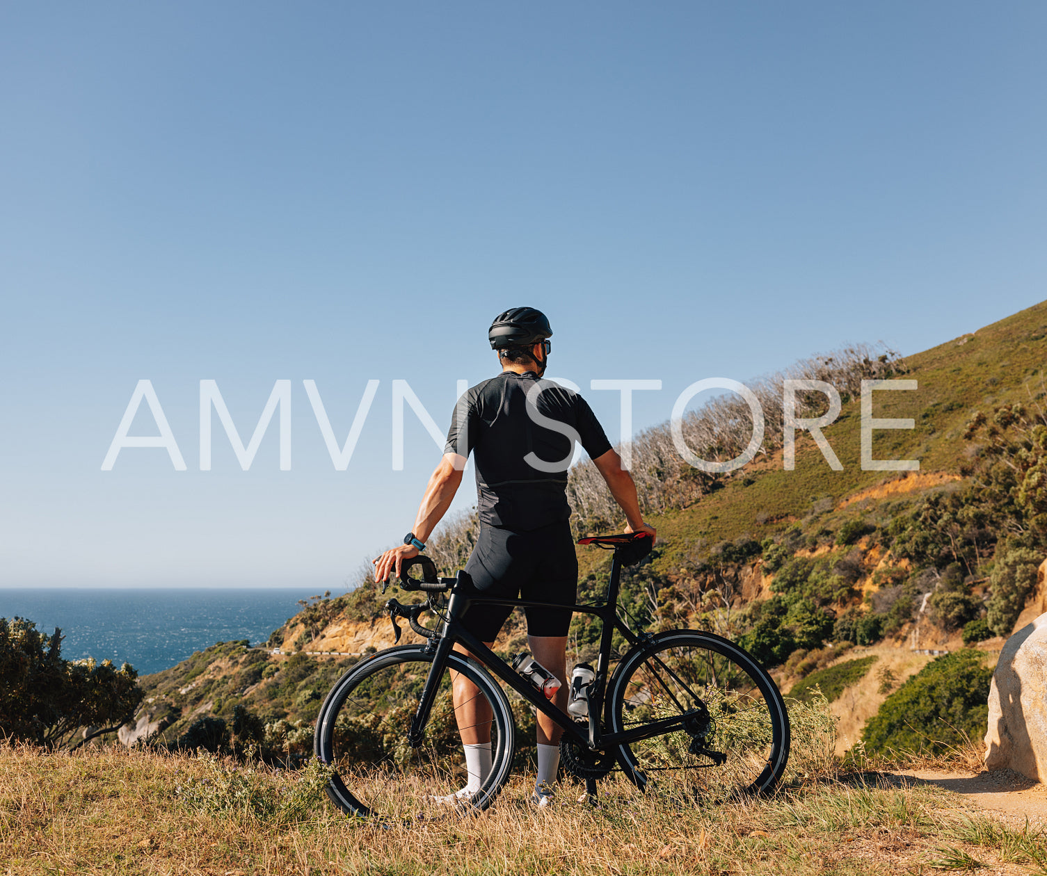 Back view of a male cyclist leaning on his road bike relaxing during training, enjoying the view