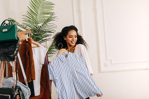 Woman trying on shirt. Beautiful vlogger posing with hanger.