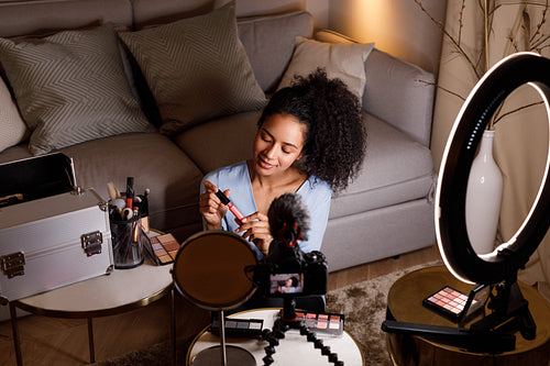 Beauty vlogger holding lipstick while recording makeup tutorial