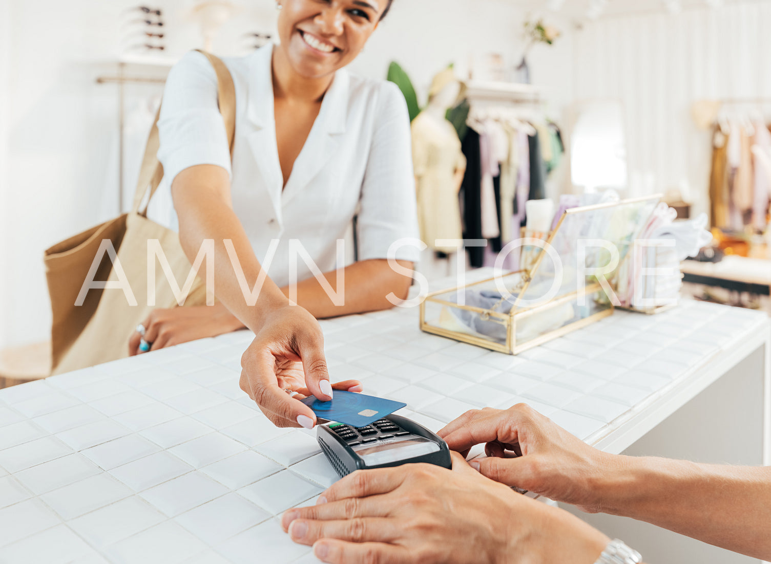 Stylish woman paying via credit card at a counter in a small clothing store