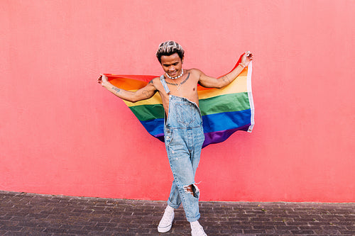 Young guy dancing with rainbow LGBT flag outdoors