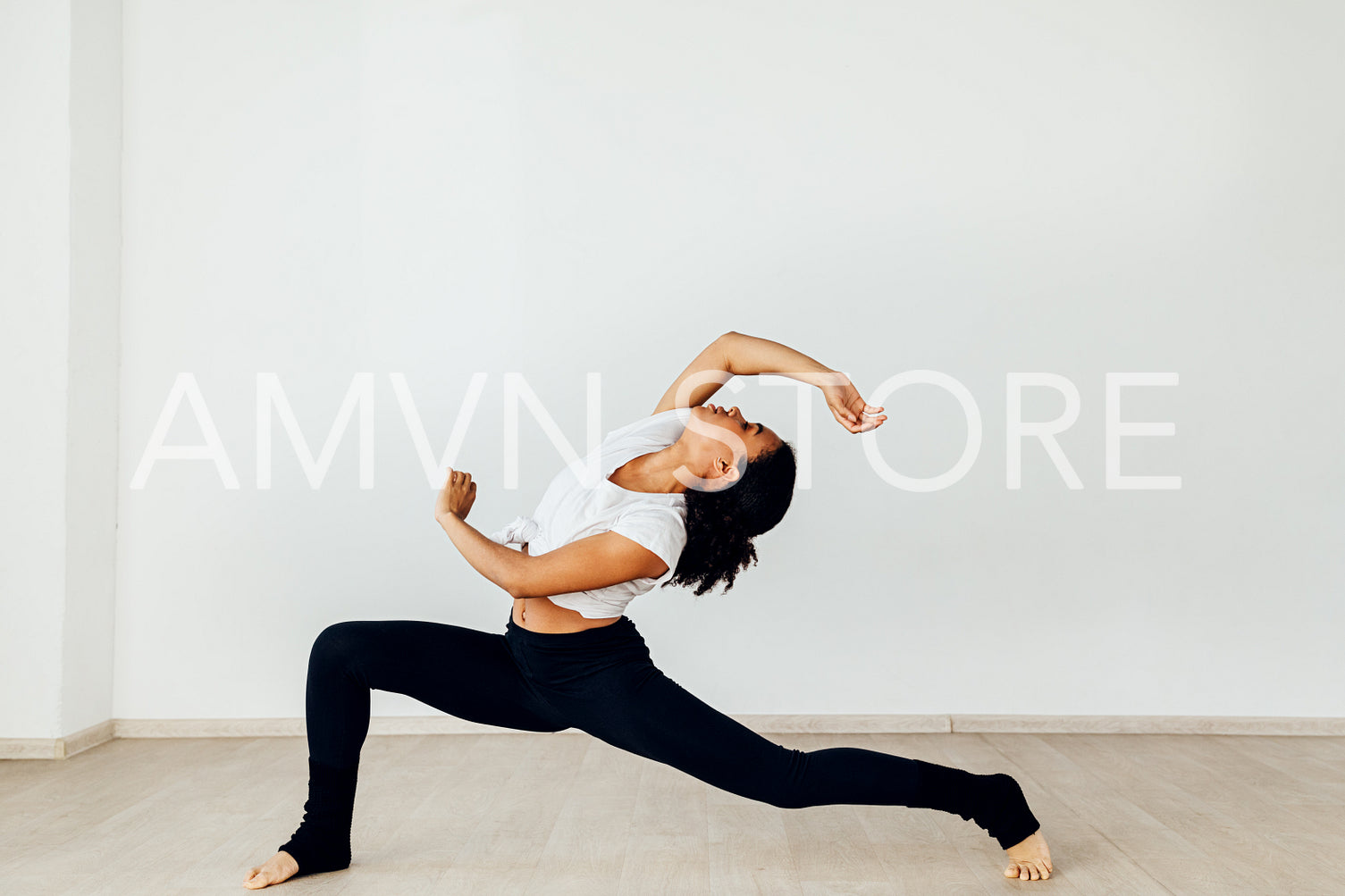 Professional female dancer performing in studio at a white wall	