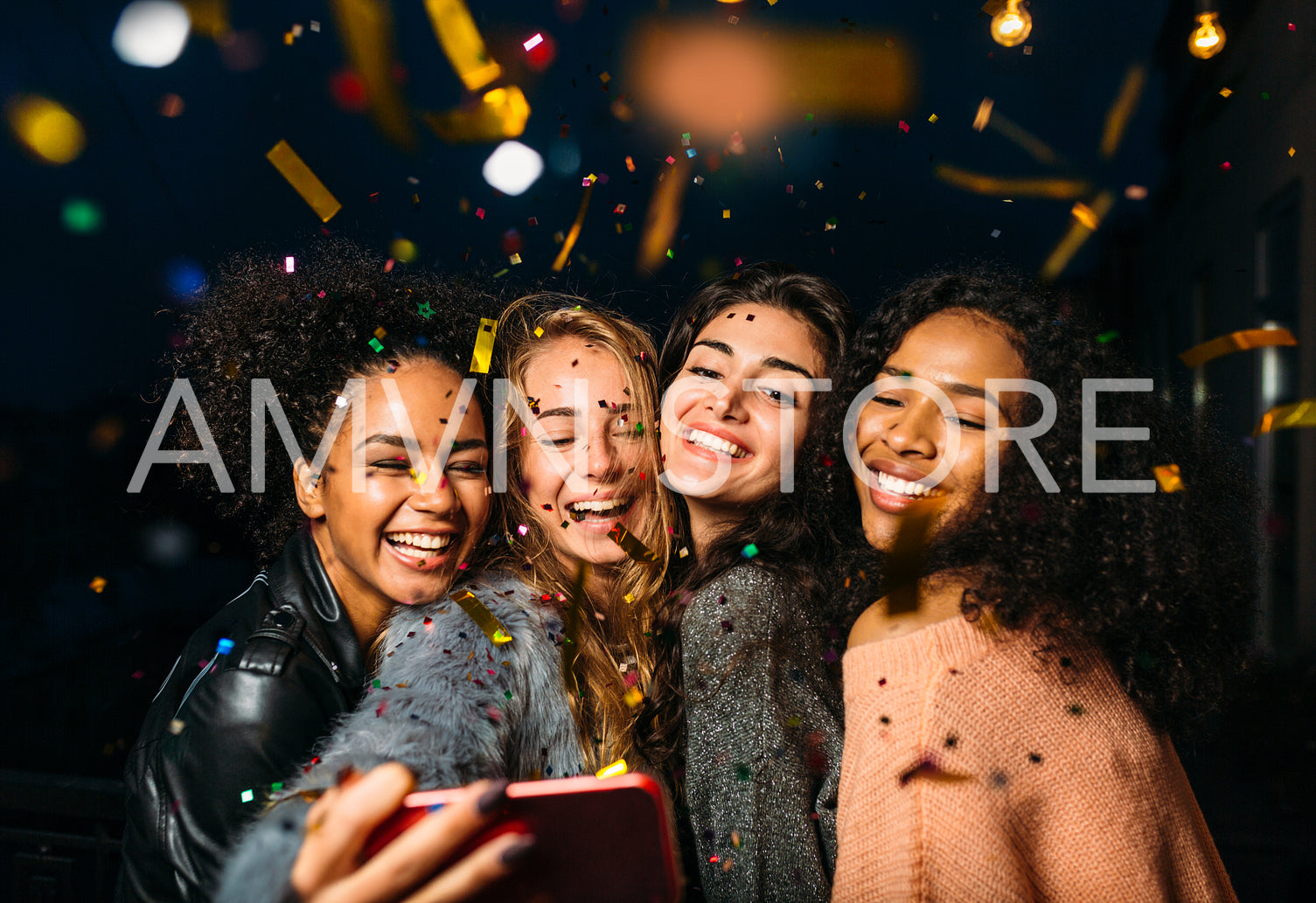 Group of happy women taking selfie on mobile phone, standing outdoors at night	