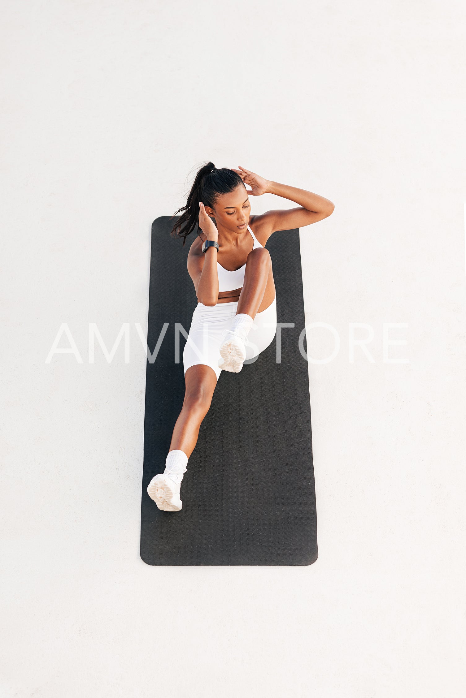 Young female doing core exercises on a mat outdoors. High angle of a woman doing abdominal exercises.