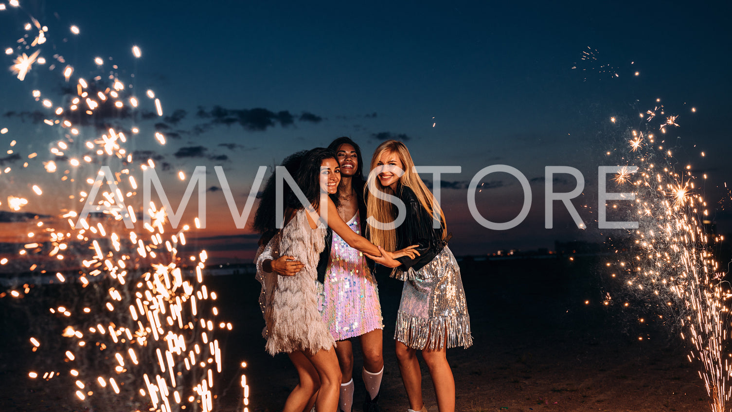 Four happy women celebrating with fireworks at sunset	