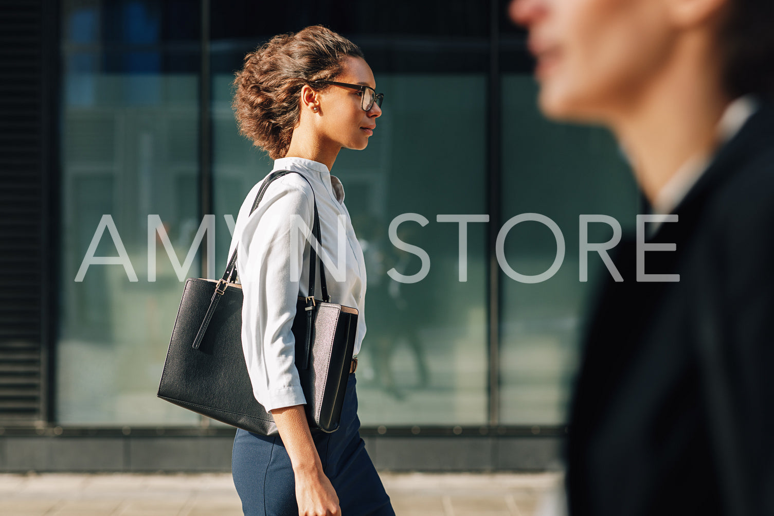 Side view of businesswoman walking outdoors carrying a bag on a city street	