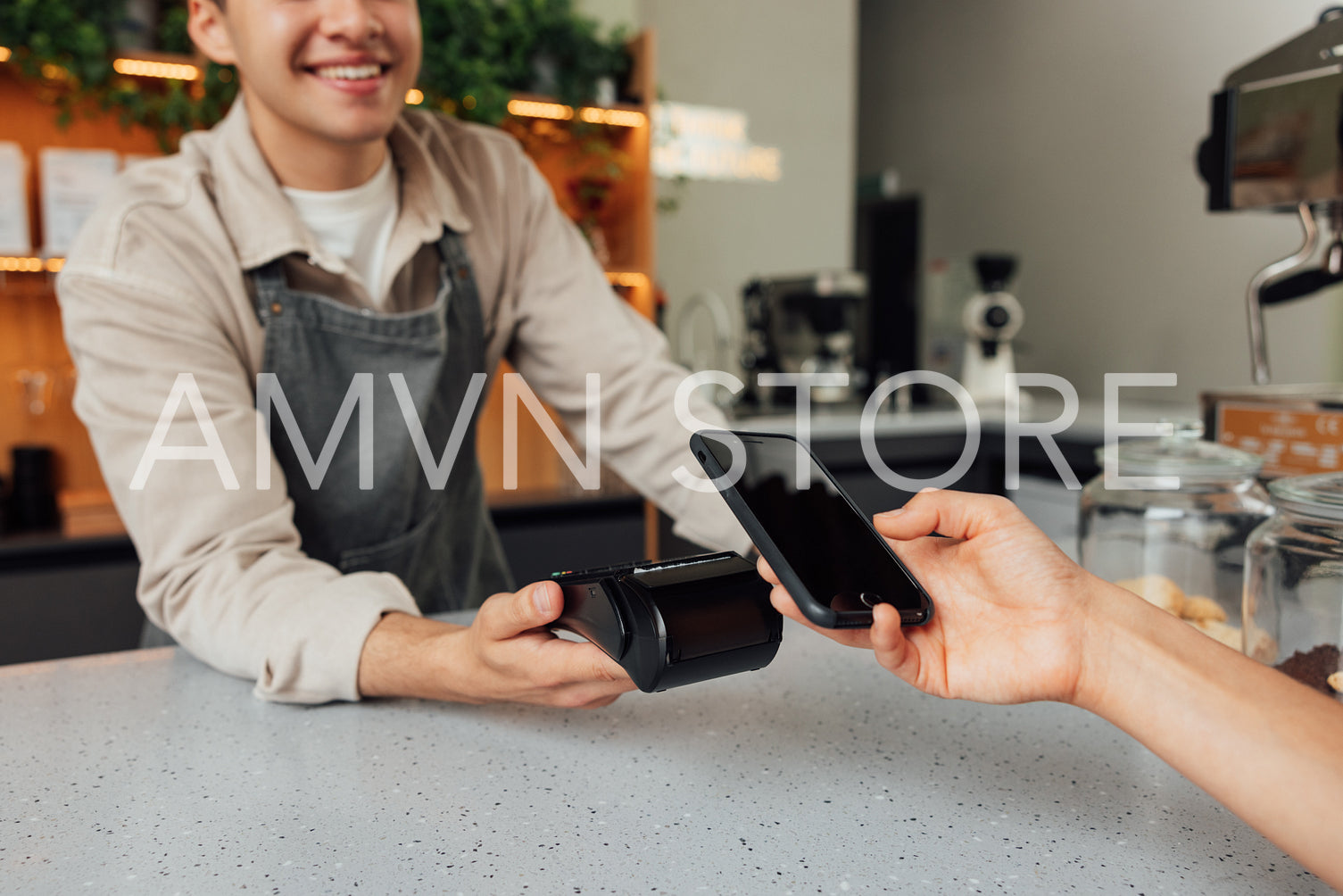 Unrecognizable cafe owner holding card machine at the counter while customer making payment by smartphone