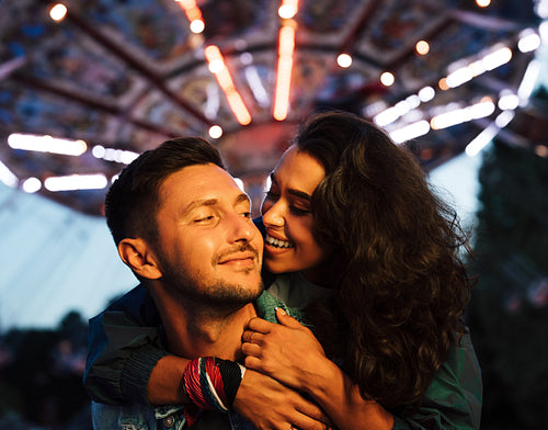 Young couple having fun ant night in amusement park