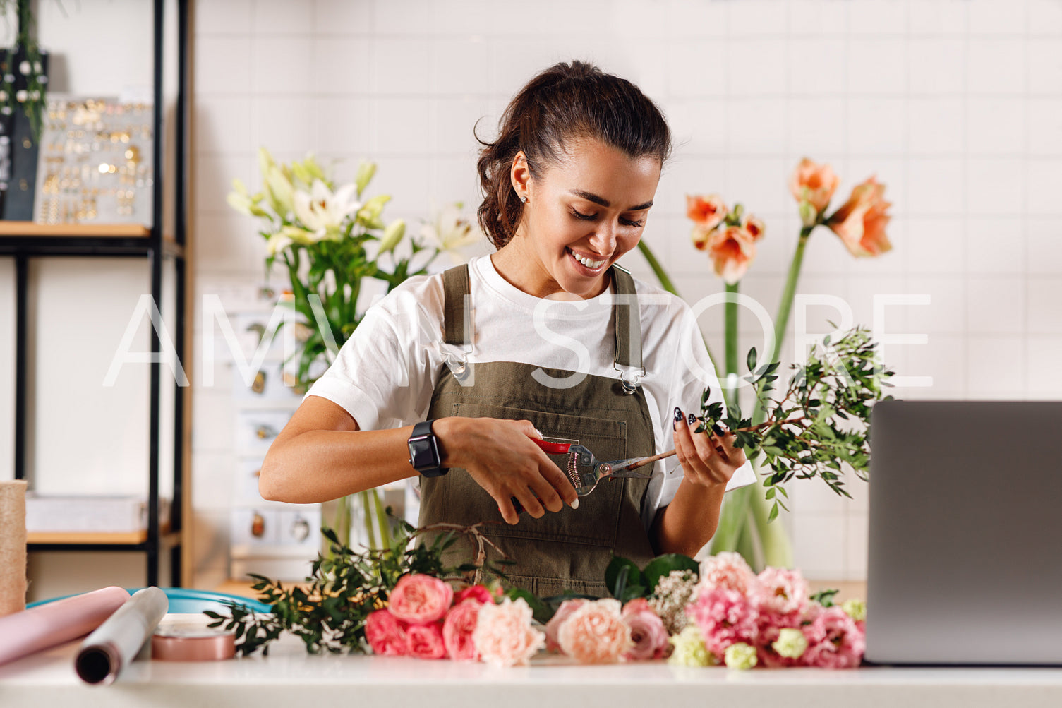 Smiling woman working at counter. Female florist cutting flowers with scissors.	