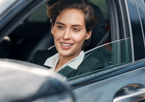 Smiling businesswoman in a car. Young female in formal wear driving a car.