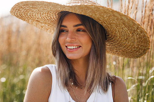 Close up portrait of a happy blond woman in sun hat looking away