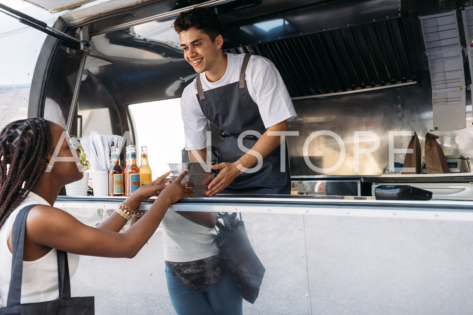 Smiling salesman giving takeaway packaged food to a female customer. Woman taking food from a food truck owner.