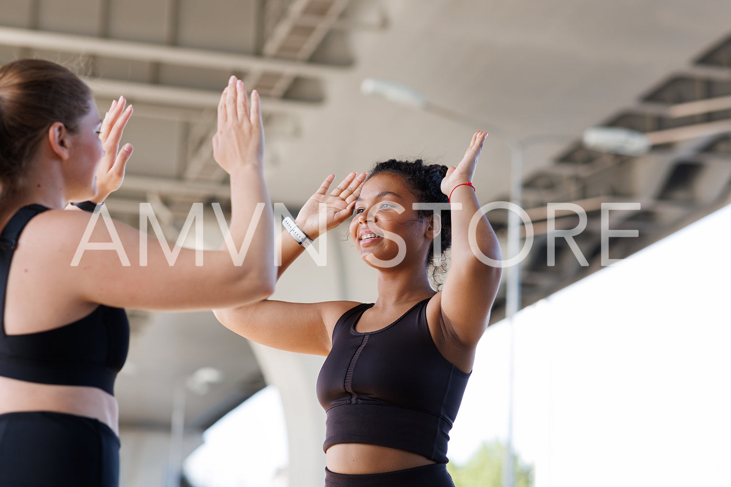 Young smiling female giving five to her fitness buddy. Two plus-size women give high five to each other after an intense workout outdoors.