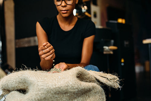 Woman inspecting fresh coffee beans in her coffee shop before roasting