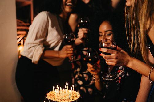 Group of four female friends celebrating birthday at home, having fun