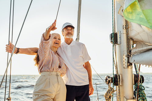 Senior couple enjoying the view on private sailboat. Retired people standing together on yacht at sea.