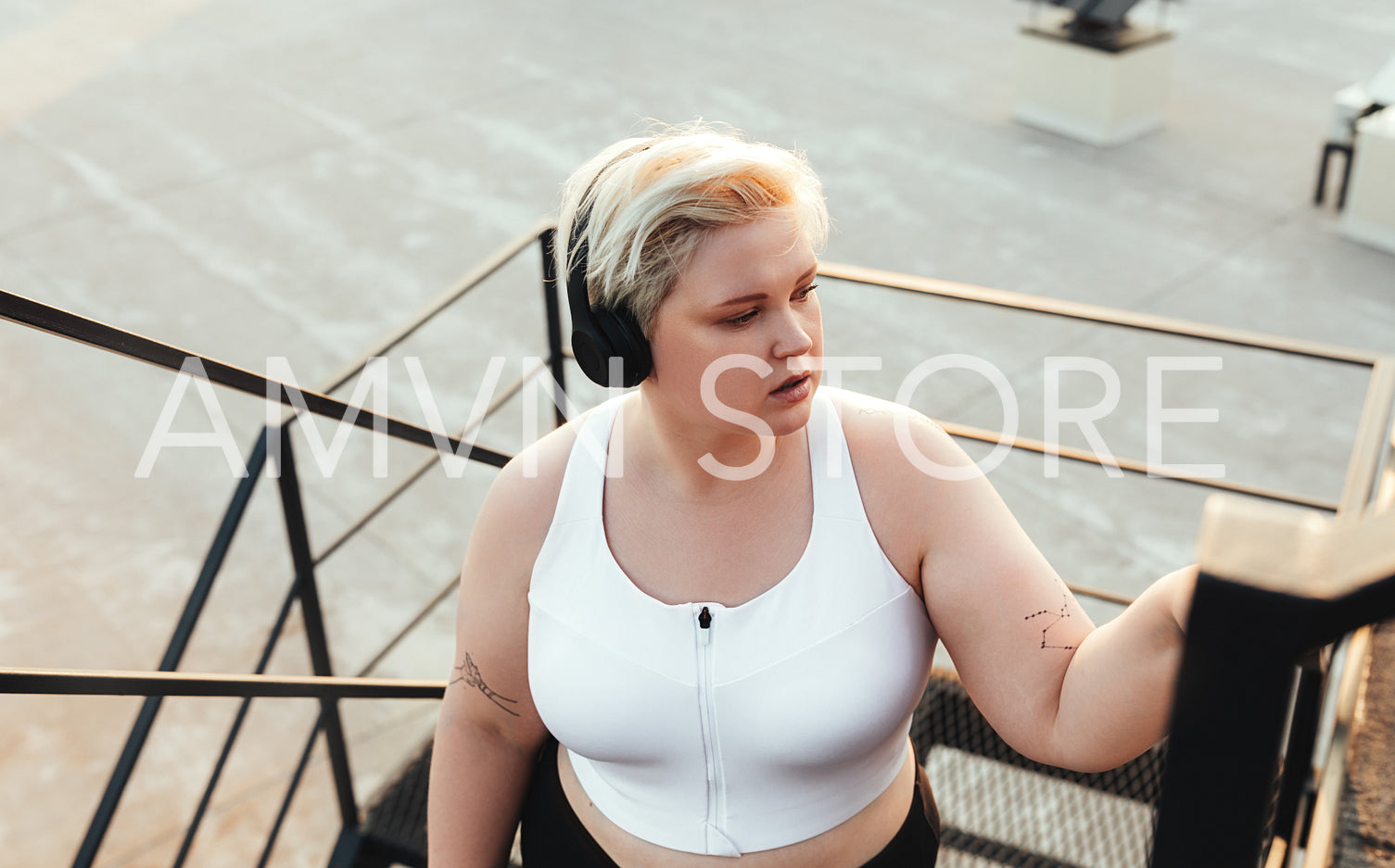 Young woman in headphones stepping up on staircase outdoors and looking away	