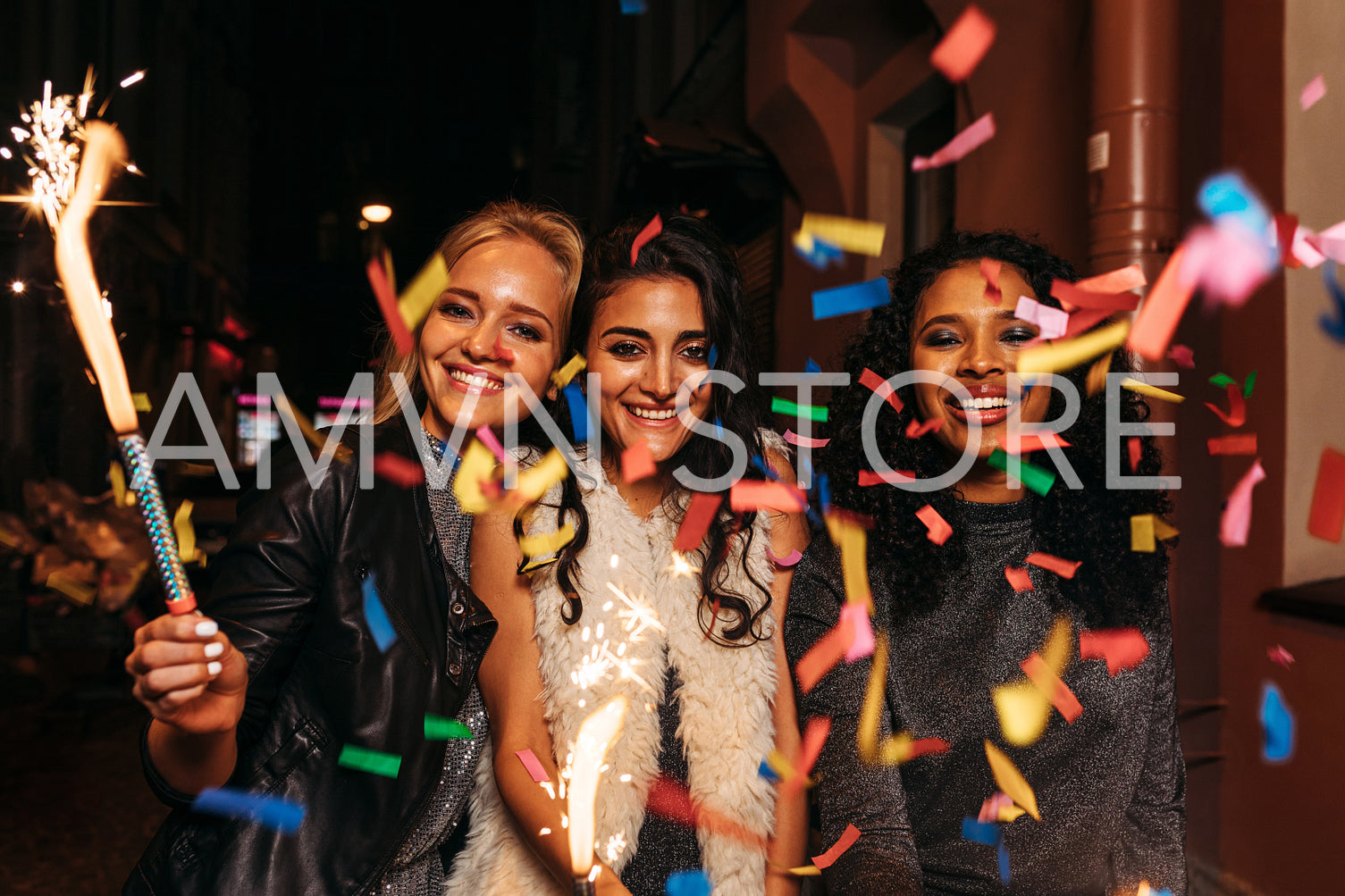 Group of friends with sparklers enjoying new years eve under confetti	